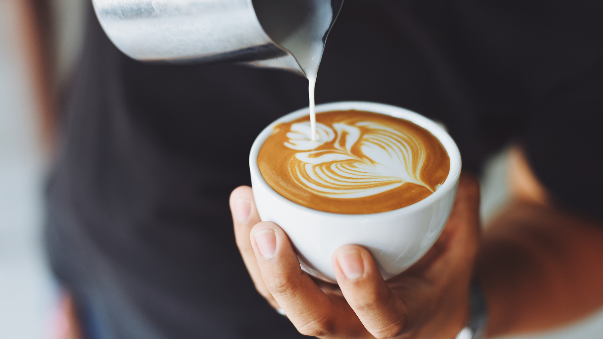 Latte art being poured in a white mug